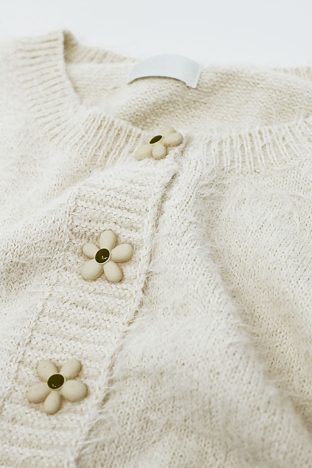 Short and fluffy cream cardigan with flower buttons Q2 Sweaters BoutiqueLua